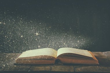abstract image of open antique book on wooden table. selective focus. retro filtered with glitter overlay