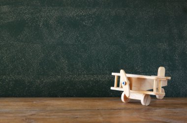 close up photo of wooden toy airplane against chalkboard