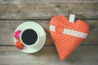 top view image of colorful heart shape chocolates, fabric heart and cup of coffee on wooden table. valentine's day celebration concept