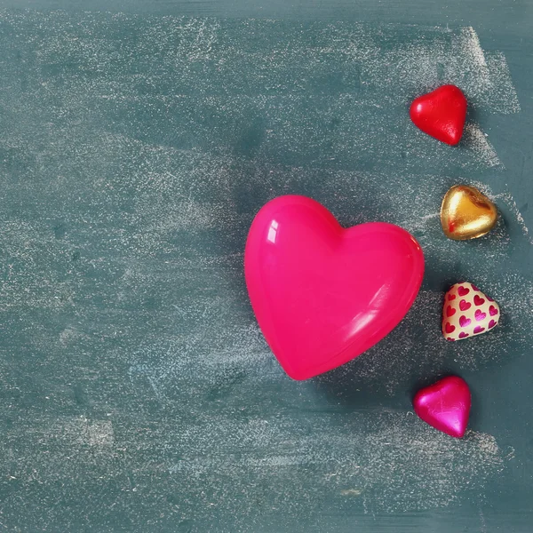 Top view image of colorful heart shape chocolates on blackboard background. valentine's day celebration concept. filtered and toned photo — 图库照片