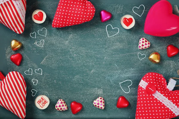 Top view image of colorful heart shape chocolates, fabric hearts on blackboard background. valentine's day celebration concept — Stockfoto