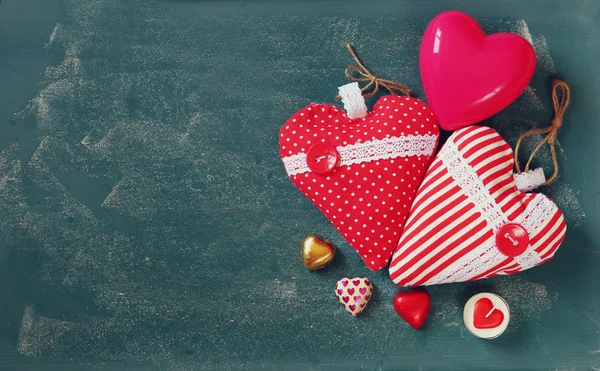 Image de vue du haut de chocolats colorés en forme de coeur, coeurs de tissu sur fond de tableau noir. concept de célébration de la Saint-Valentin — Photo