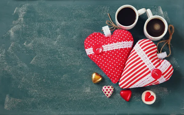 Imagem vista superior de chocolates forma de coração colorido e canecas casal de café no fundo quadro-negro. Conceito de celebração do dia dos namorados — Fotografia de Stock