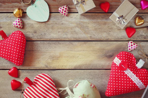 Top view image of colorful heart shape chocolates, fabric hearts and gift boxes on wooden table. valentine's day celebration concept — Stockfoto