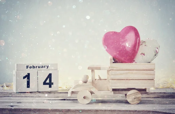 14. února dřevěné vinobraní kalendář s dřevěných hraček kamion s srdce před tabuli. koncept oslavu Valentýna. ročník, filtrován s třpytky překrytí — Stock fotografie