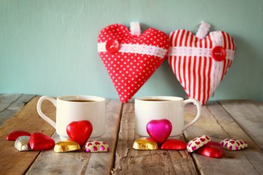 iki kırmızı kalp şekli çikolata ve iki bardak kahve ahşap masa üzerinde görüntü. Sevgililer günü kutlama kavramı. Filtre vintage