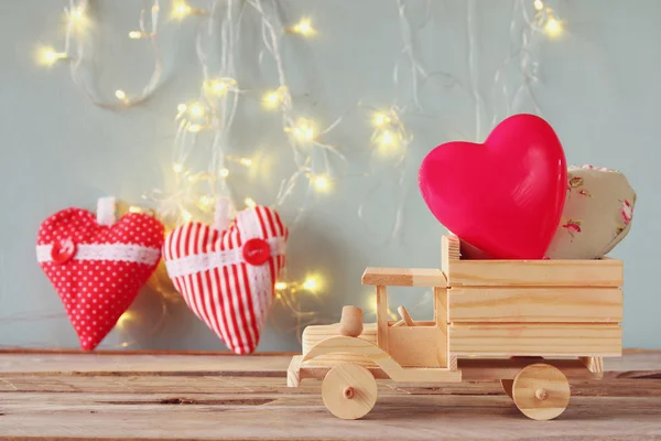 Foto de camión de juguete de madera con corazones delante de pizarra. Concepto de celebración del día de San Valentín. filtrado vintage — Foto de Stock