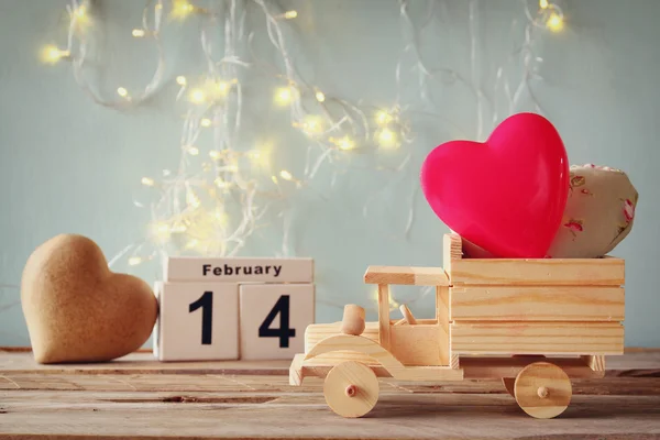 Fotografie din 14 februarie calendar vintage din lemn cu camion de jucărie din lemn cu inimi în fața tablei de cretă. Conceptul de sărbătoare Valentine 's Day. vintage filtrate — Fotografie, imagine de stoc