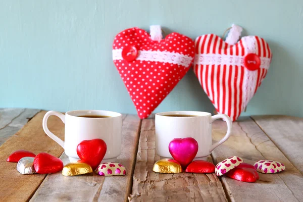 Imagem de rebocar chocolates forma de coração vermelho e copos de café casal na mesa de madeira. Conceito de celebração do dia dos namorados. vintage filtrado — Fotografia de Stock