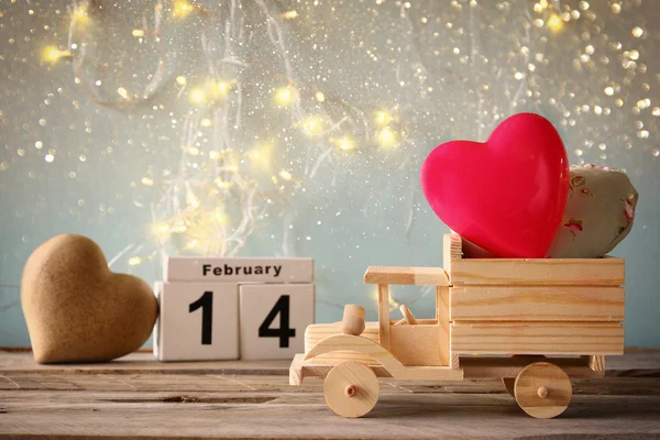 Foto del 14 de febrero calendario vintage de madera con camión de juguete de madera con corazones delante de pizarra. Concepto de celebración del día de San Valentín. filtrado vintage —  Fotos de Stock