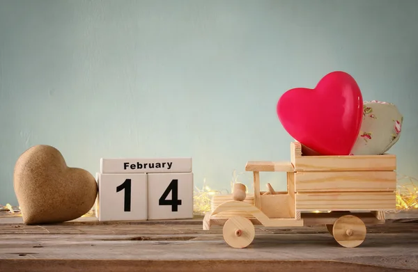 14 de febrero calendario vintage de madera con camión de juguete de madera con corazones en frente de pizarra. Concepto de celebración del día de San Valentín. filtrado vintage —  Fotos de Stock