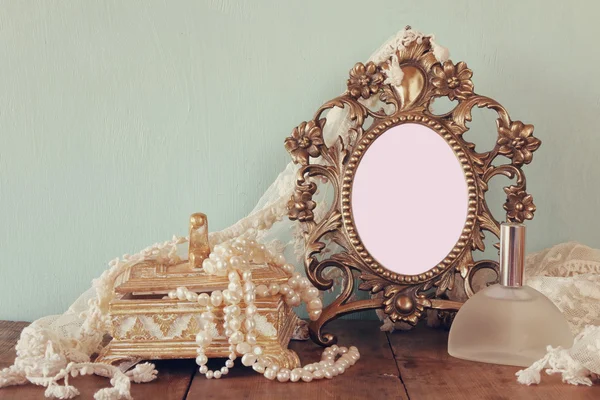 Antique blank victorian style frame, perfume bottle and white pearls on wooden table. template, ready to put photography — Stock fotografie