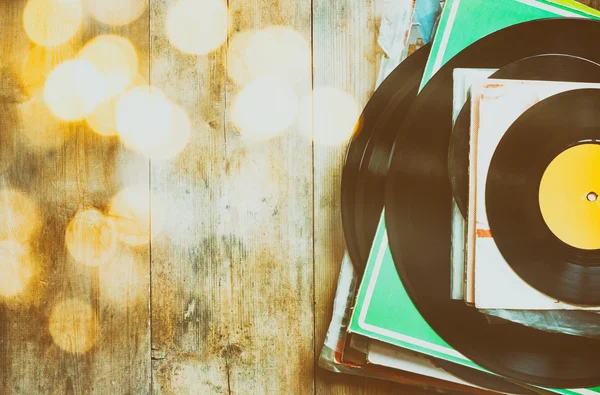 Records stack over wooden table and vintage light leaks. filtered image — Stock Fotó