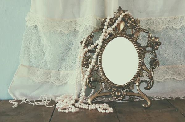 Marco de estilo victoriano en blanco antiguo, y perlas blancas en mesa de madera. imagen retro filtrada y tonificada. plantilla, listo para poner la fotografía —  Fotos de Stock