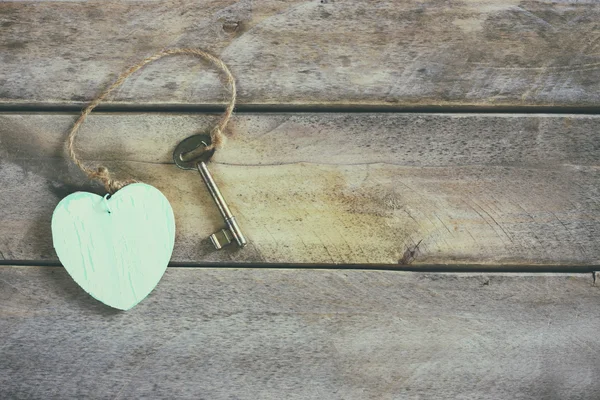 Top view of old vintage key with a wooden heart on wooden background — Stock Photo, Image