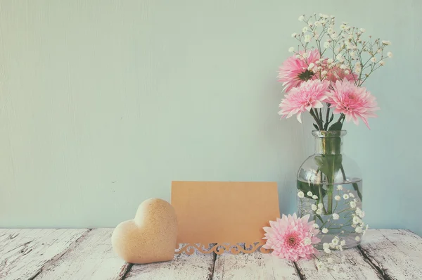 Vitt och rosa blommor, hjärta bredvid vintage tomma kort över träbord — Stockfoto