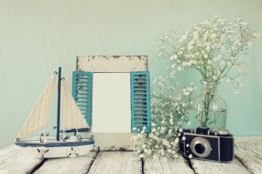 eski vintage ahşap çerçeve, beyaz çiçekler, fotoğraf makinesi ve yelkenli tekne ahşap masa üzerinde. Vintage filtre uygulanan görüntü. Deniz yaşam tarzı kavramı. Fotoğraf koymak hazır şablon