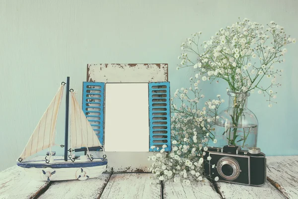 Oude vintage houten frame, witte bloemen, fotocamera en zeilboot op houten tafel. Vintage gefilterde afbeelding. nautische lifestyle concept. sjabloon, klaar om fotografie — Stockfoto