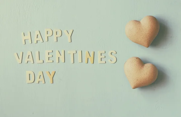Οι λέξεις "ευτυχισμένη ημέρα του Αγίου Βαλεντίνου" γίνονται με μπλοκ ξύλινα γράμματα δίπλα σε δύο καρδιές σε ανοιχτό μπλε ξύλινο φόντο. vintage φιλτραρισμένο και ήπια — Φωτογραφία Αρχείου