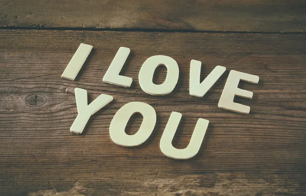 选择性焦点照片的字"我爱你"，用木质背景的块木字母。情人节庆祝概念。复古过滤和色调 — 图库照片