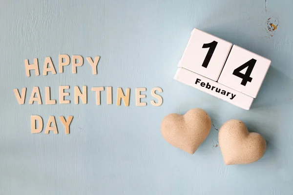 14 de febrero calendario vintage de madera y las palabras "feliz día de San Valentín" hecho con letras de madera bloque junto a un par de corazones sobre fondo de madera azul claro —  Fotos de Stock