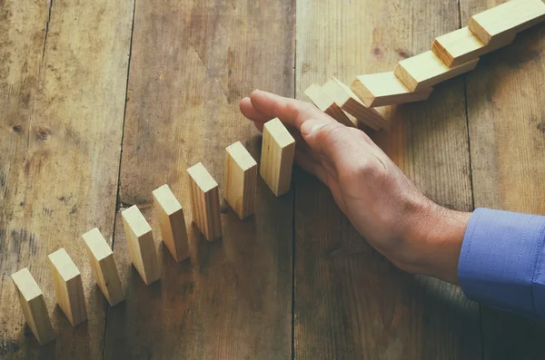 Eine männliche Hand, die den Dominoeffekt stoppt. Retro-Image und Risikokontrollkonzept — Stockfoto