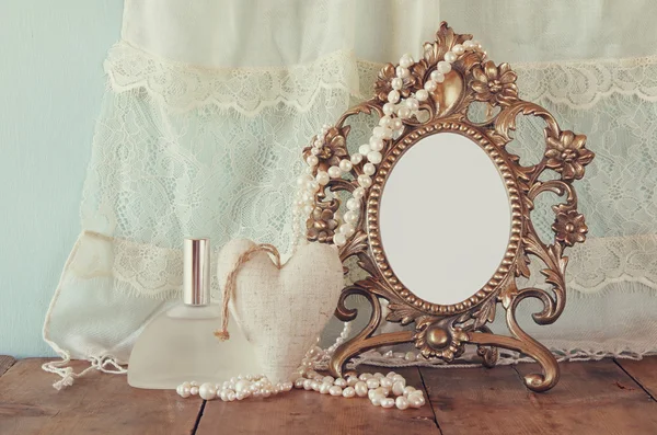 Antique blank victorian style frame, perfume bottle and white pearls on wooden table. retro filtered and toned. template, ready to put photography — Stock fotografie