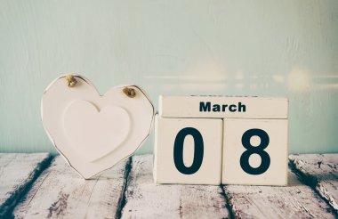 vintage filtered image of wooden March 8 calendar, next to white heart on old rustic table. selective focus