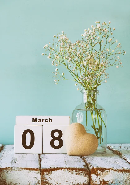 Legno 8 marzo calendario, accanto al cuore e fiori bianchi su vecchio tavolo rustico. focus selettivo — Foto Stock