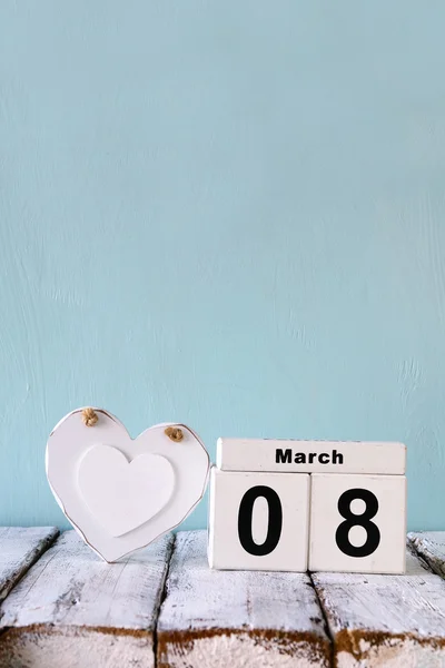 Vintage filtered image of wooden March 8 calendar, next to white heart on old rustic table. selective focus — Φωτογραφία Αρχείου