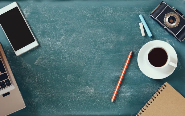 Top view image of mobile phone, cup of coffee and laptop over blackboard background — 图库照片
