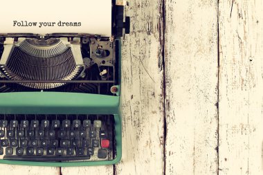 top view photo of vintage typewriter with the phtase: follow your dreams, on wooden table. retro filtered image