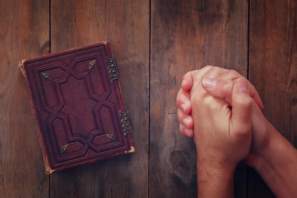 Obrazem: pohled shora mans ruce složené v modlitbě u modlitební kniha. koncept pro náboženství, duchovno a víra — Stock fotografie