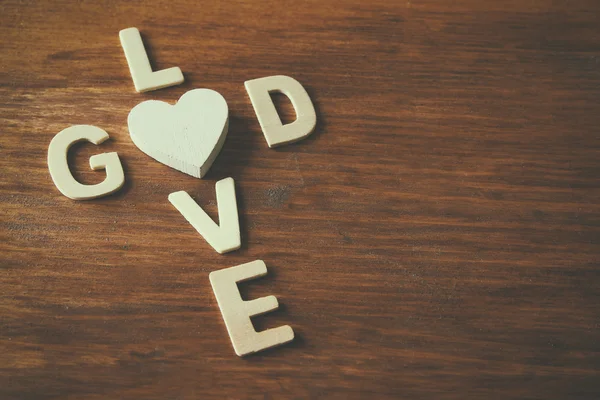 Selective focus photo of The words love is god made with block wooden letters on wooden background. religion concept — Stock Photo, Image