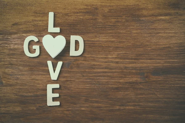 Foto foco seletivo de As palavras amor é deus feito com letras de madeira bloco no fundo de madeira. conceito de religião — Fotografia de Stock