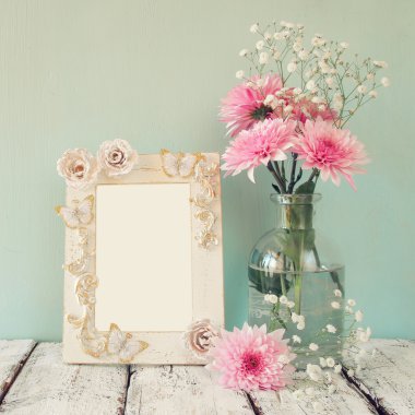 pembe ve beyaz çiçekler ve antika çerçeve ahşap masa üzerinde görüntü. Filtre vintage.