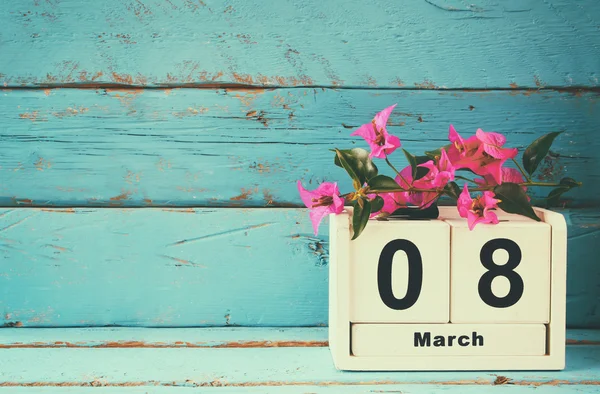 Wooden March 8 calendar, next to purple flowers on old blue rustic table. selective focus. vintage filtered — Stock Photo, Image