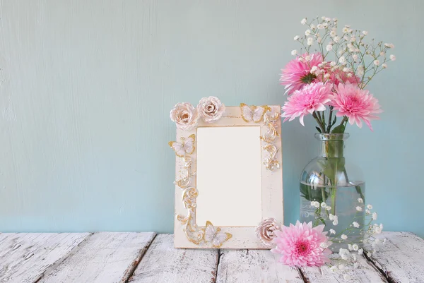 Immagine di fiori rosa e bianchi e cornice antica su tavolo in legno. modello, pronto a mettere la fotografia — Foto Stock