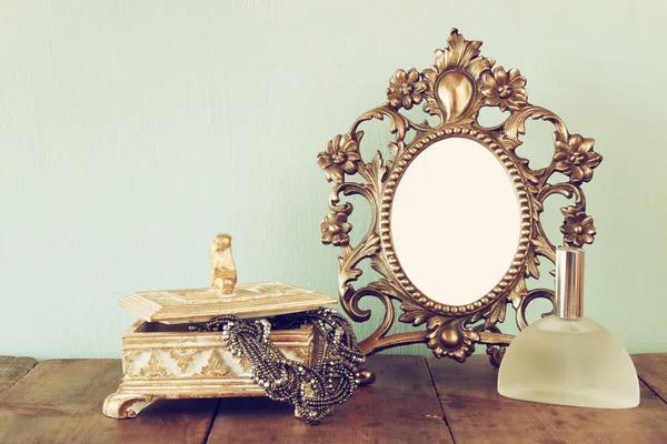 Antique blank victorian style frame, perfume bottle and neckless on wooden table. retro filtered image. template, ready to put photography — Stockfoto