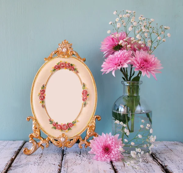Imagen de flores rosas y blancas y marco antiguo sobre mesa de madera. filtrado vintage. plantilla, listo para poner la fotografía — Foto de Stock