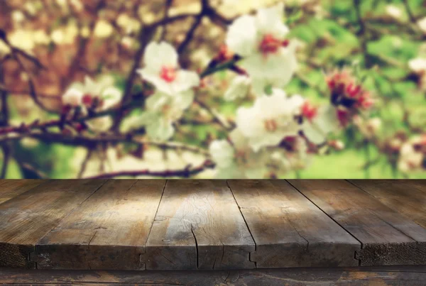 Mesa rústica de madeira na frente da árvore de flores de cereja branca de primavera. imagem filtrada vintage. exposição do produto e conceito do piquenique — Fotografia de Stock