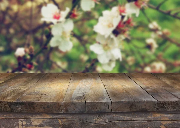 Mesa rústica de madeira na frente da árvore de flores de cereja branca de primavera. imagem filtrada vintage. exposição do produto e conceito do piquenique — Fotografia de Stock