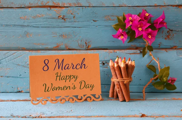 Vintage card with phrase: 8 march happy womens day on wooden texture table next to purple bougainvillea flower. — 스톡 사진