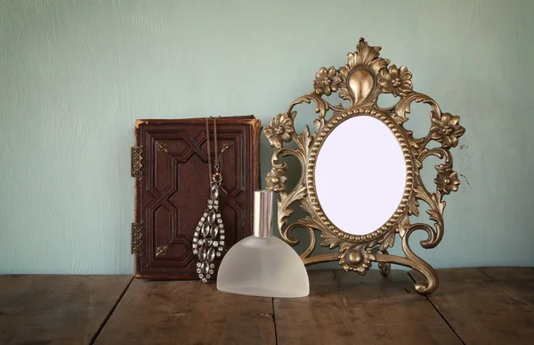 Antique blank Victorian style frame and old book with vintage necklace on wooden table. retro filtered image. template, ready to put photography — Stock fotografie