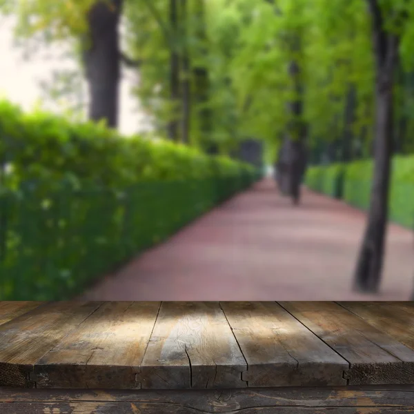 Wood board table in front of spring park alley trees background. Ready for product display montages — Stock Photo, Image