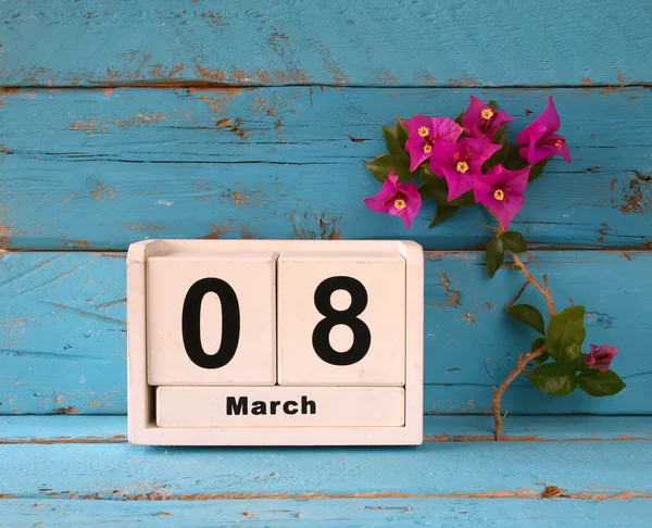 Holzkalender vom 8. März, daneben lila Blumen auf altem blau-rustikalem Tisch. Selektiver Fokus. — Stockfoto