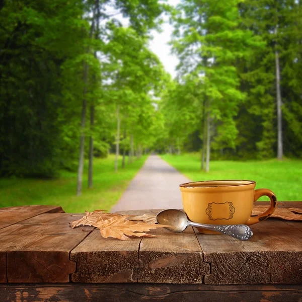 Imagen frontal de la taza de café sobre la mesa de madera frente al fondo del bosque —  Fotos de Stock