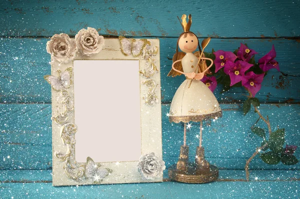 Imagen de blanco vintage marco en blanco y linda princesa de hadas en la mesa de madera. vintage filtrado con superposición de brillo —  Fotos de Stock