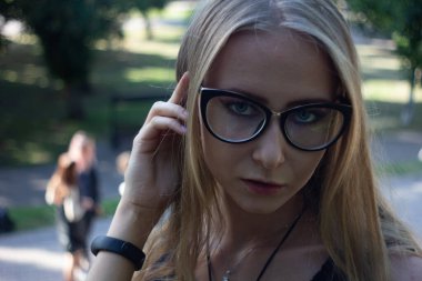 Güneşli havada parkta gözlüklü bir kız.