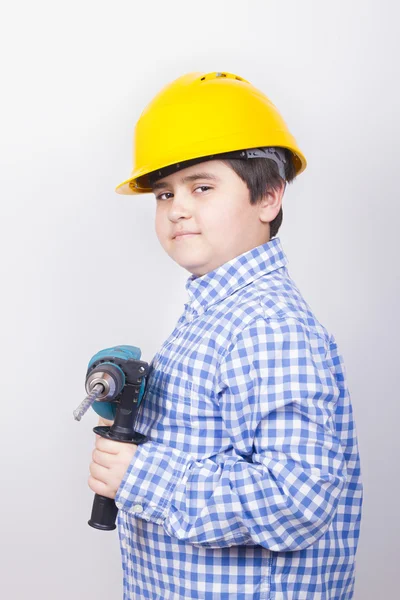 Niño con un taladro en casco amarillo — Foto de Stock